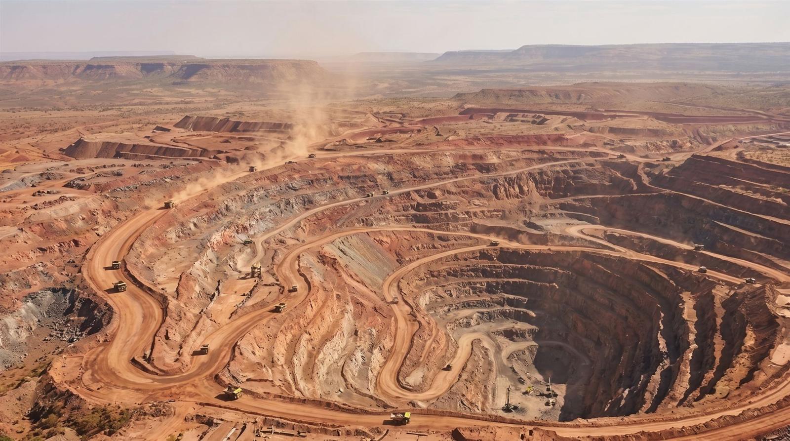 Aerial view of an open-pit mine with haul trucks on the ramps